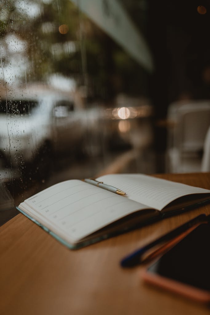 A cozy close-up of an open notebook and pen on a wooden table by a rainy window.
what I’m carrying into the new year