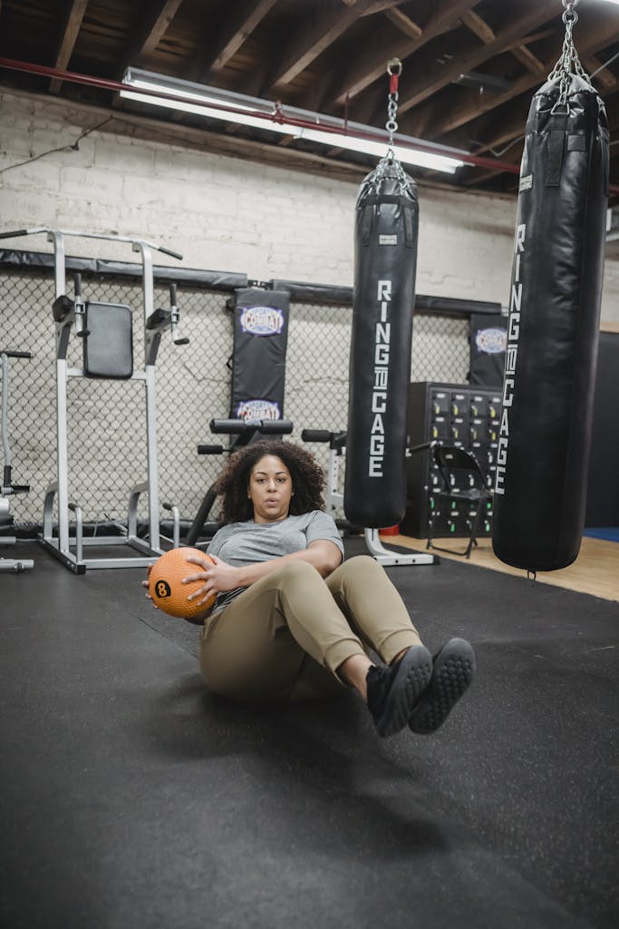 Plus-size woman performing core exercises with a medicine ball in a modern gym setting.