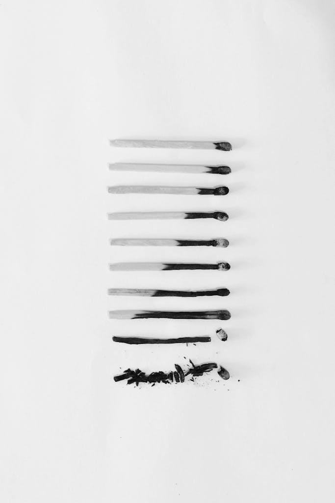 Artistic black and white image of burned matches arranged on a white background, symbolizing burnout.
