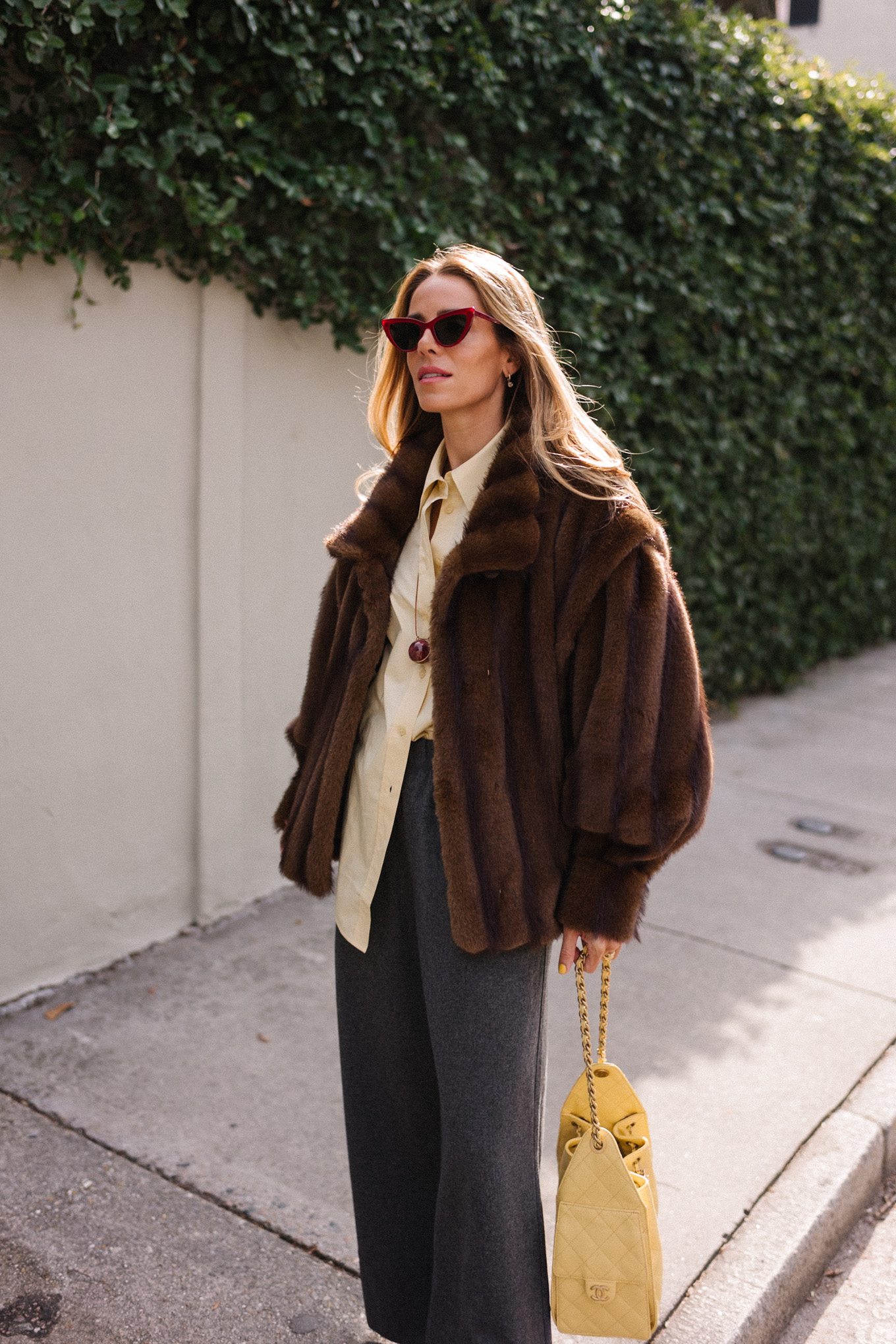 brown faux fur coat yellow button down shirt grey pants yellow tote red flats