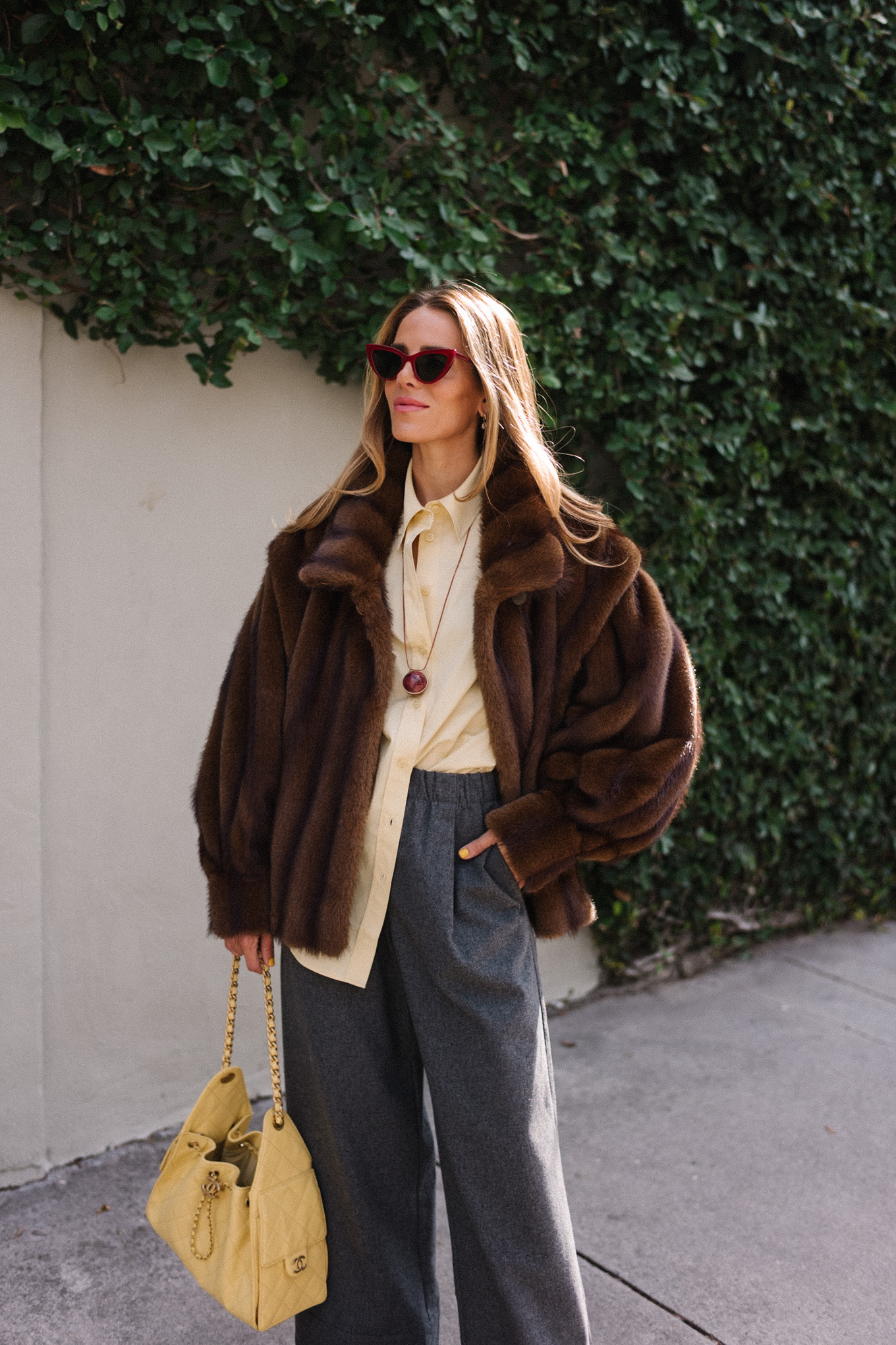 brown faux fur coat yellow button down shirt grey pants yellow tote red flats