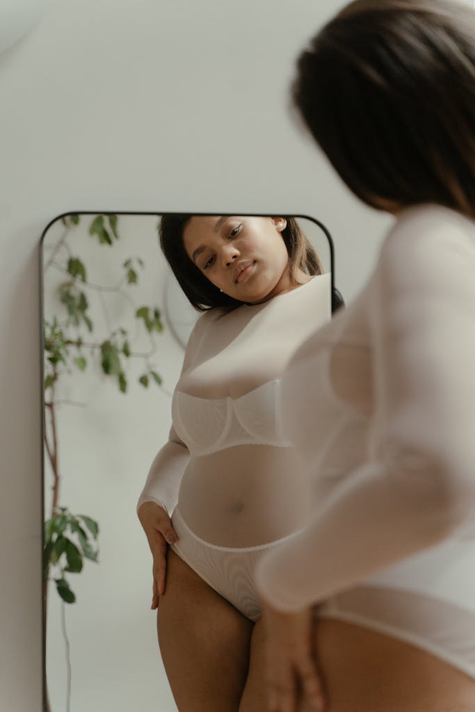 A woman embraces self-love and body positivity in a reflective mirror portrait. Self-trust